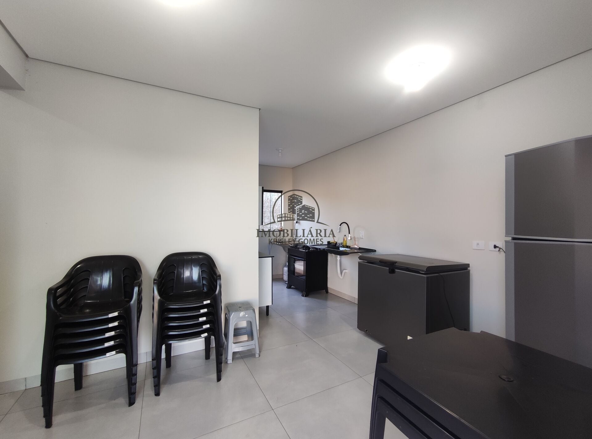 Cozinha equipada com geladeira, freezer e cadeiras