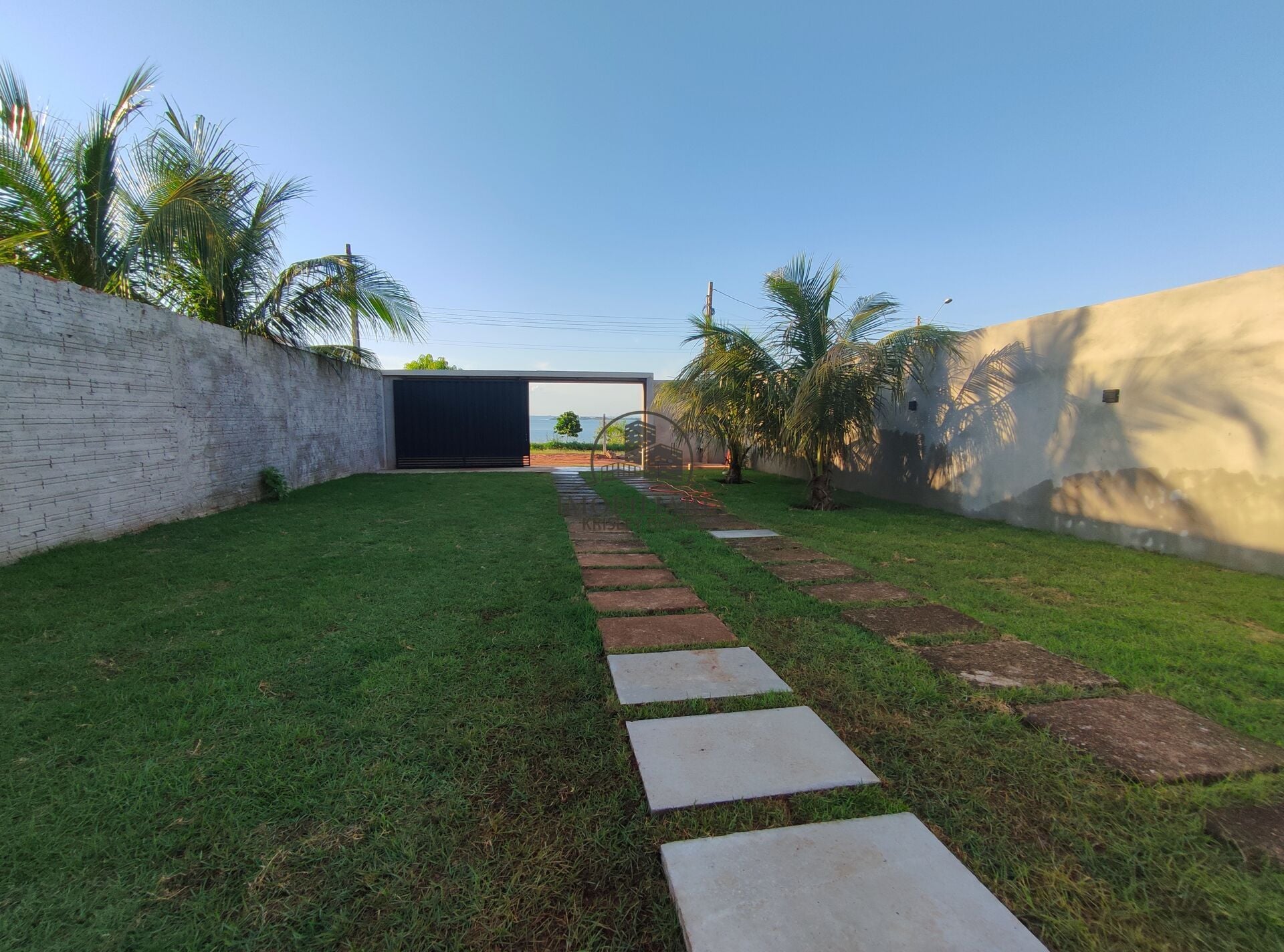 Jardim lateral com caminho de pedras e portão
